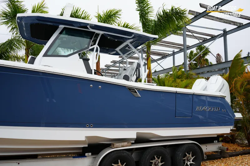 Slide: The Image of 2026 Blackfin 332 CC boat in blue on trailer, surrounded by palm trees. - 4