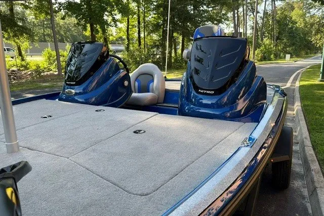 Slide: The Image of 2026 Nitro Z17 boat with dual consoles and plush seating, parked on a tree-lined road. - 8