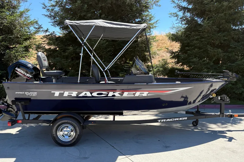 The Image of 2026 Tracker Pro Guide V-16 SC boat with canopy on trailer, outdoors. - 0
