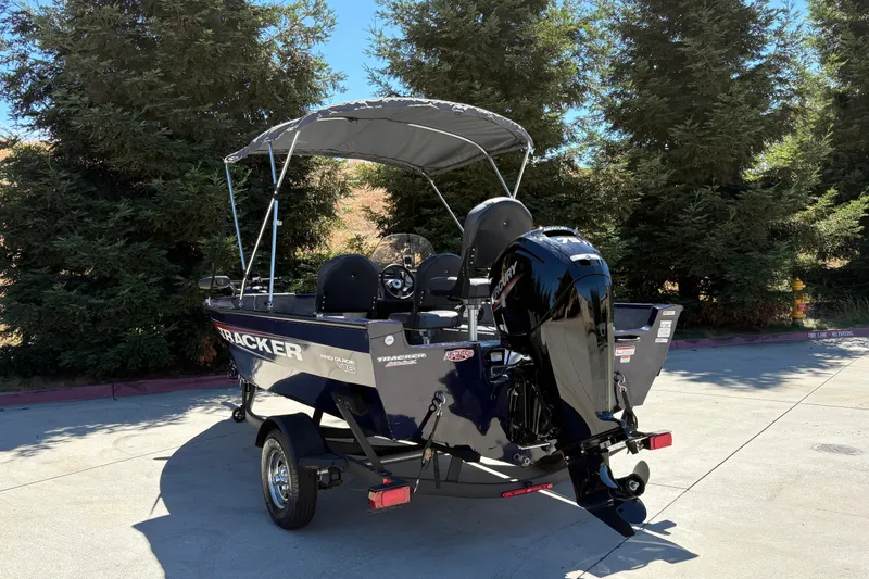Slide: The Image of 2026 Tracker Pro Guide V-16 SC boat with canopy, parked outdoors. - 12