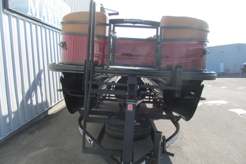 Slide: The Image of 2026 Regency 230 DL pontoon boat on trailer, parked near a building. - 3