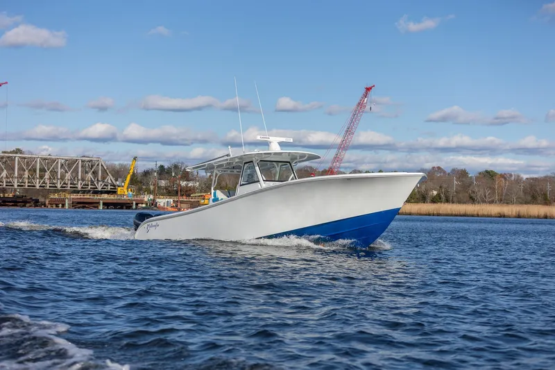 Slide: The Image of 2018 Yellowfin 39 Offshore boat cruising on a river with a bridge in the background. - 2
