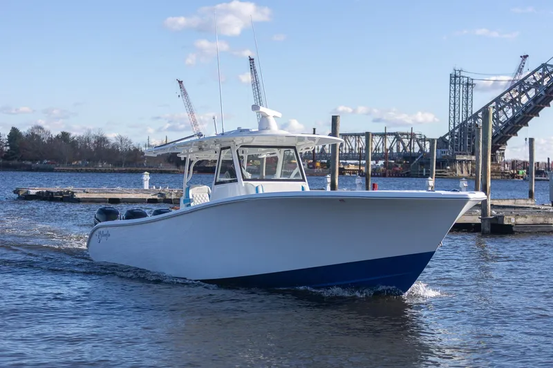 Slide: The Image of 2018 Yellowfin 39 Offshore boat cruising near a dock with bridge in background. - 63