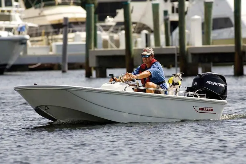 Slide: The Image of Manufacturer Provided Image: Man driving a 2020 Boston Whaler 110 Sport boat on the water. - 12
