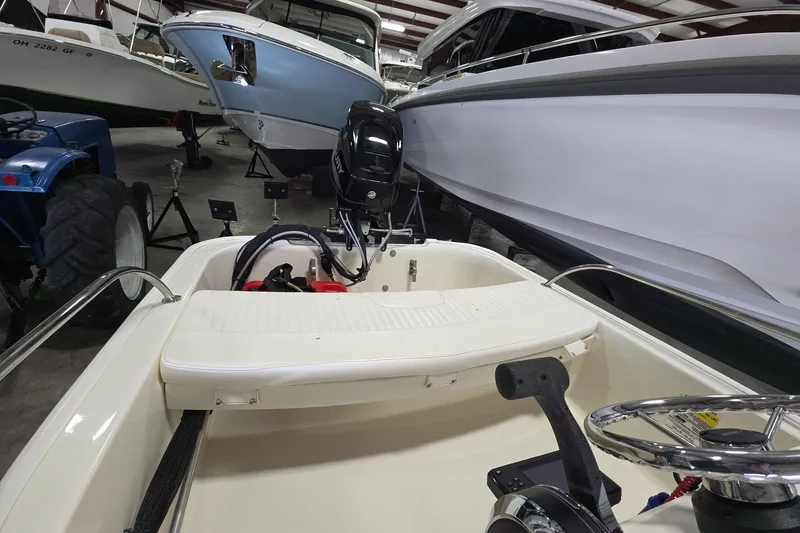 Slide: The Image of 2020 Boston Whaler 110 Sport boat in storage, featuring a sleek interior and outboard motor. - 9