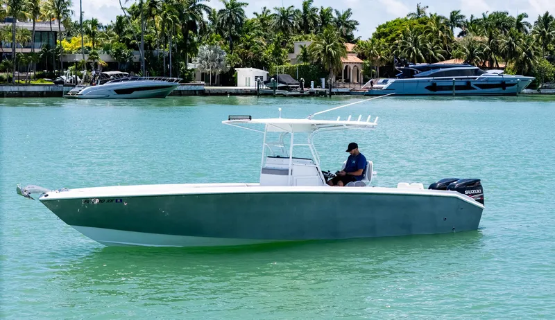 The Image of 1999 Monza 31 boat on calm water, featuring Suzuki outboard engines, with a person at the helm. - 0