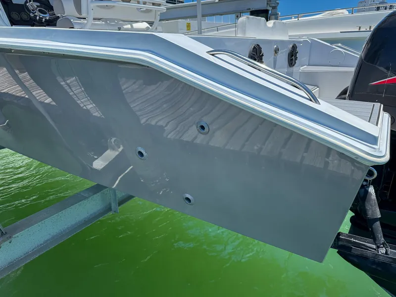 Slide: The Image of 1999 Monza 31 boat stern with outboard motor, docked on green water. - 27