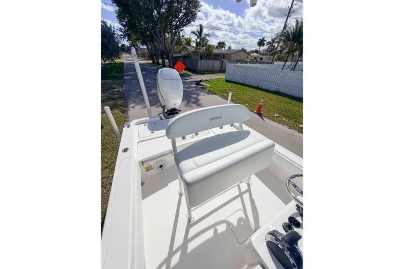 Slide: The Image of 2023 Contender 26 Bay boat interior with seating and steering wheel, parked on a sunny street. - 10