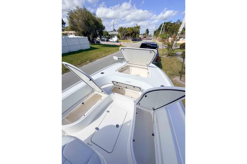 Slide: The Image of 2023 Contender 26 Bay boat with open storage compartments on a sunny day. - 11