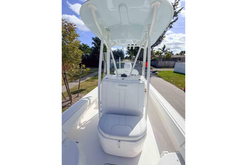Slide: The Image of 2023 Contender 26 Bay boat with T-top and seating, parked on a sunny street. - 12