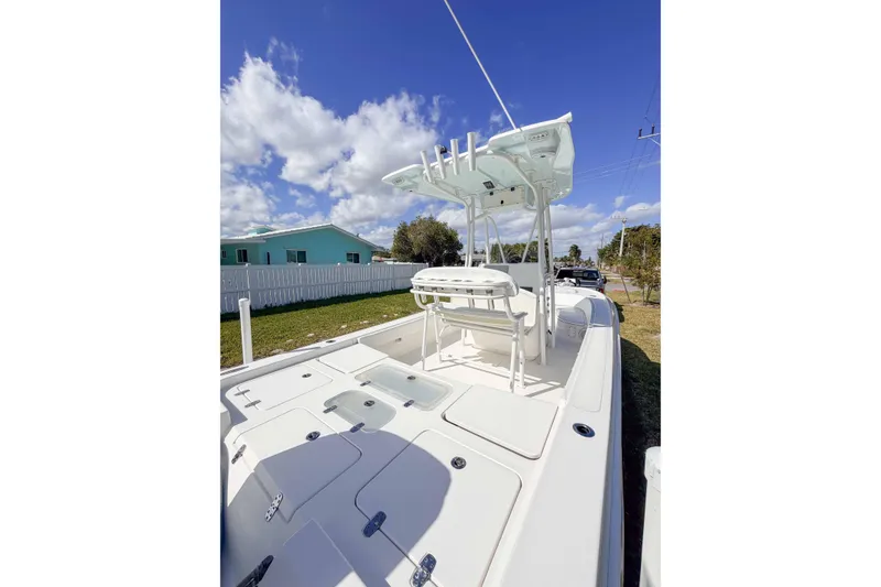 Slide: The Image of 2023 Contender 26 Bay boat with T-top, parked outdoors under a blue sky. - 16
