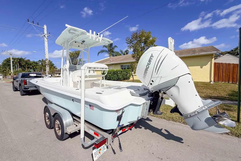 Slide: The Image of 2023 Contender 26 Bay boat on trailer, parked on suburban street, clear sky background. - 2