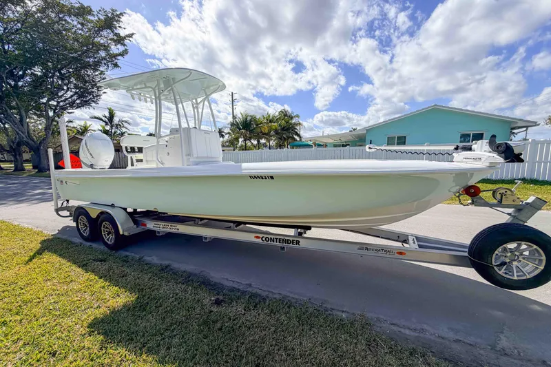 Slide: The Image of 2023 Contender 26 Bay boat on trailer, parked outdoors under a partly cloudy sky. - 4