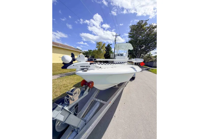 Slide: The Image of 2023 Contender 26 Bay boat on trailer under clear blue sky. - 5