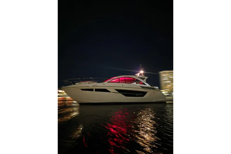 Slide: The Image of 2018 Cruisers Yachts 50 Cantius docked by palm trees and waterfront homes. - 2