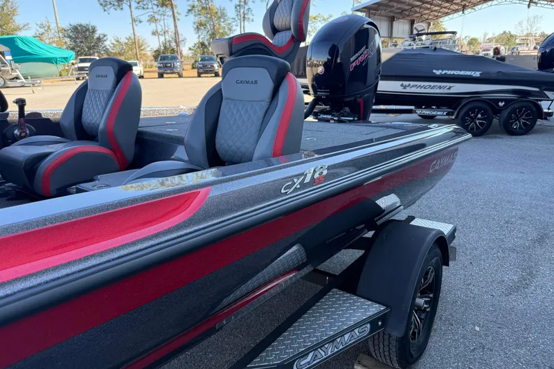 Slide: The Image of 2022 Caymas CX 18 SS boat with red and gray seating, parked outdoors. - 2