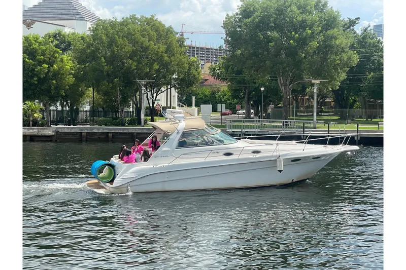 The Image of 1998 Sea Ray Sundancer 330 yacht cruising on a sunny day with passengers onboard. - 1