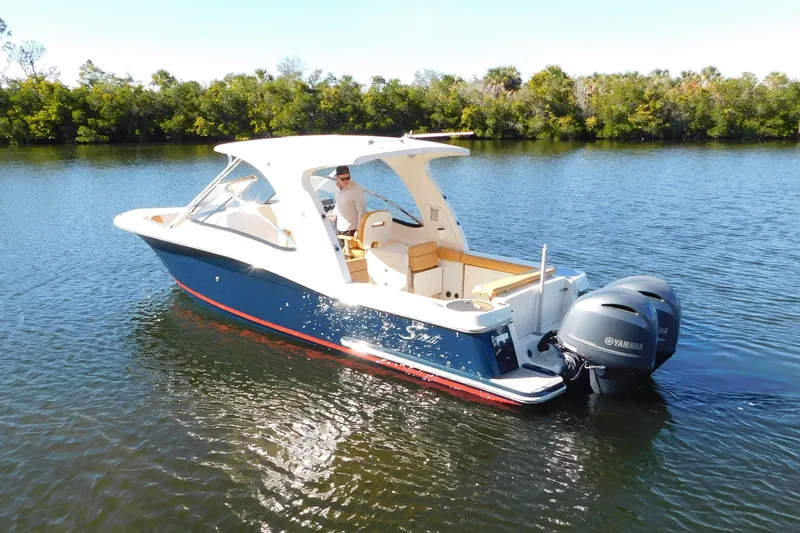 The Image of 2015 Scout 275 Dorado boat with dual Yamaha engines on a calm lake. - 0