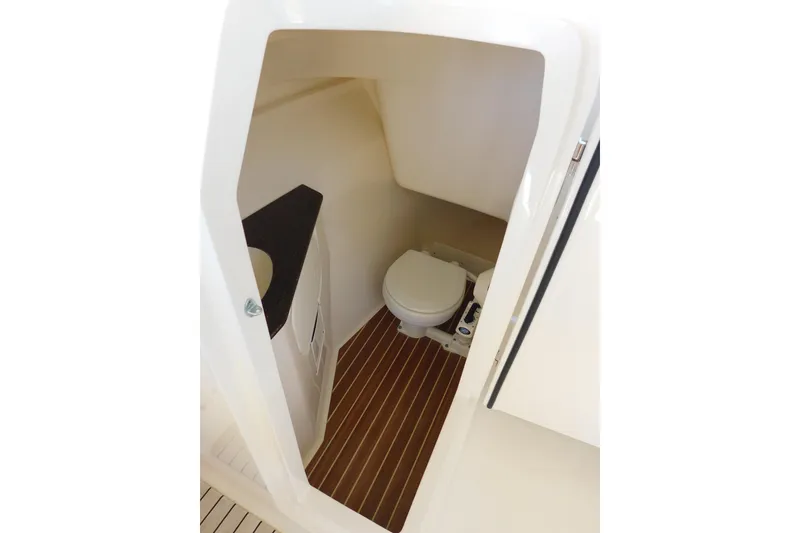 Slide: The Image of 2015 Scout 275 Dorado boat interior with compact marine toilet and wood-patterned flooring. - 23