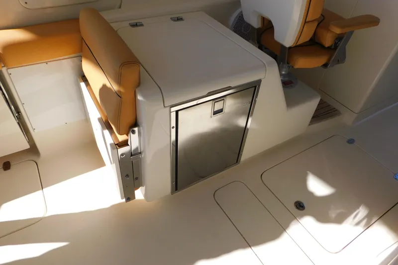 Slide: The Image of 2015 Scout 275 Dorado boat interior with tan seating and storage compartment. - 28