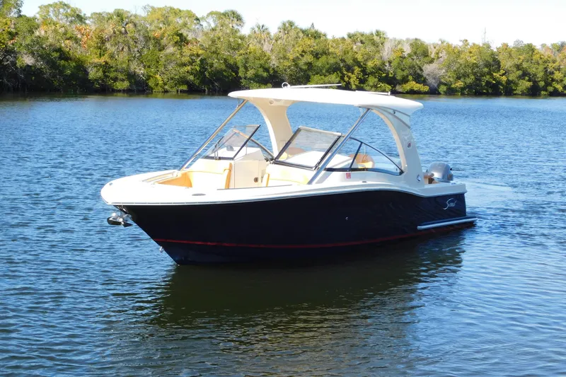 Slide: The Image of 2015 Scout 275 Dorado boat on calm water with lush green trees in the background. - 3