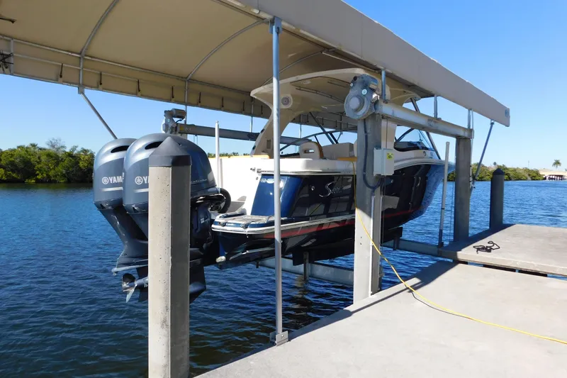 Slide: The Image of 2015 Scout 275 Dorado boat on lift with dual Yamaha engines, docked by the water. - 33