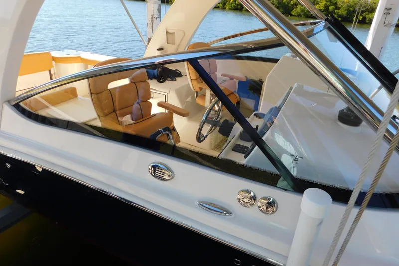 Slide: The Image of 2015 Scout 275 Dorado boat interior with tan seating and steering wheel, docked by water. - 8