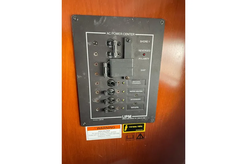 Slide: The Image of AC power center panel on a 2003 Beneteau 423 sailboat, featuring circuit breakers and warning labels. - 38