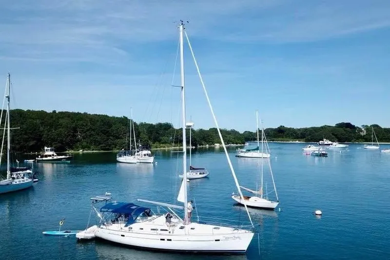 Slide: The Image of 2003 Beneteau Oceanis Clipper 423 sailboat anchored in a serene bay with other boats. - 9