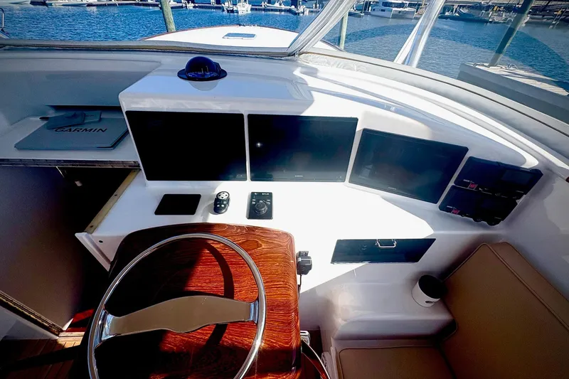 Slide: The Image of 1991 Garlington 44 Express yacht helm with modern navigation displays and wooden steering wheel. - 10