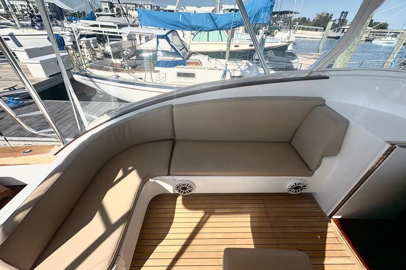 Slide: The Image of 1991 Garlington 44 Express yacht with cushioned seating and wooden deck at marina. - 12