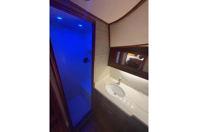 Slide: The Image of 1991 Garlington 44 Express yacht bathroom with blue-lit shower and modern sink. - 25