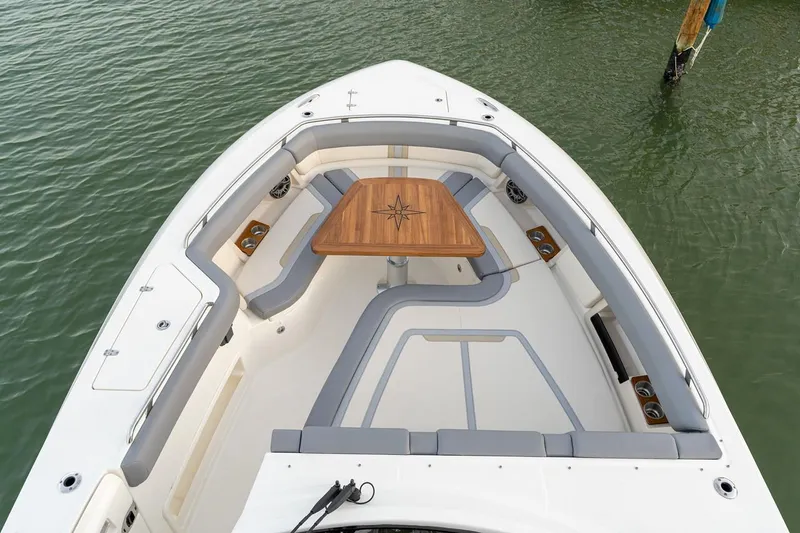 Slide: The Image of Manufacturer Provided Image: Boston Whaler 380 Realm 2026 boat interior with seating and wooden table on water. - 4