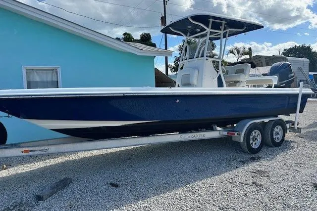 The Image of 2014 ShearWater 25 LTD boat on trailer, parked beside a blue house. - 1