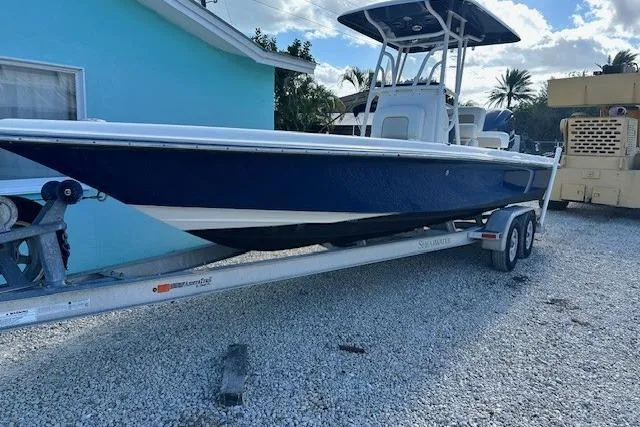 Slide: The Image of 2014 ShearWater 25 LTD boat on trailer, parked beside a blue house. - 2