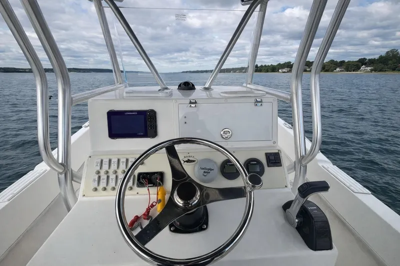 Slide: The Image of Cockpit view of a 2017 Dusky 252 boat on open water, featuring steering wheel and controls. - 7