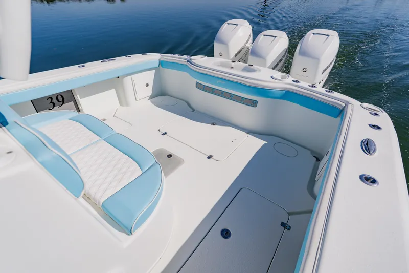 Slide: The Image of 2015 Yellowfin 39 Offshore boat interior with triple engines, featuring white and blue seating. - 30