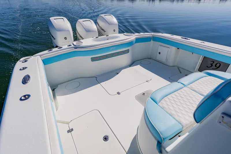 Slide: The Image of 2015 Yellowfin 39 Offshore boat interior with triple engines, featuring white and blue seating. - 31