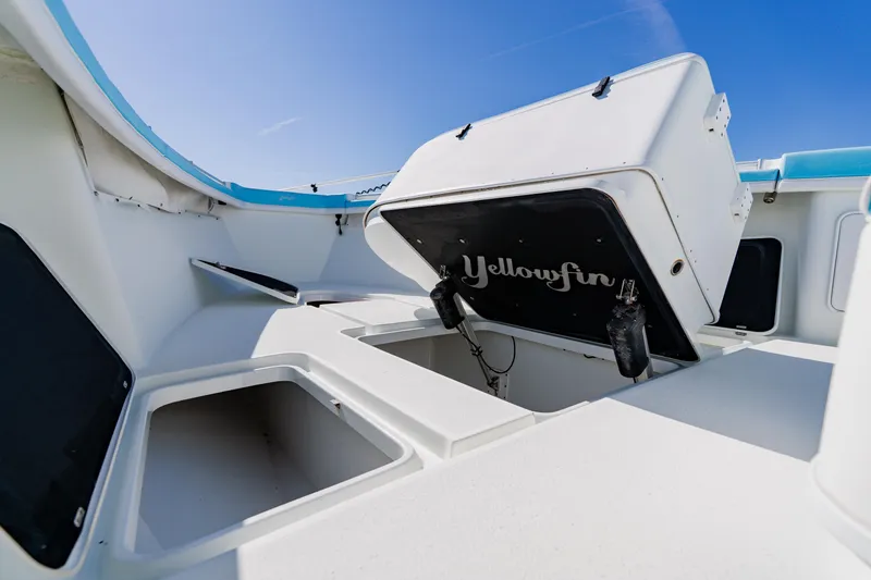 Slide: The Image of 2015 Yellowfin 39 Offshore boat interior with open storage compartments under clear blue sky. - 9