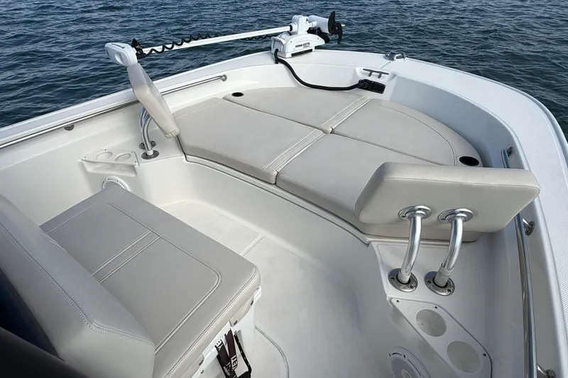 Slide: The Image of 2024 Boston Whaler 210 Montauk boat interior with cushioned seating and fishing rod holders. - 11