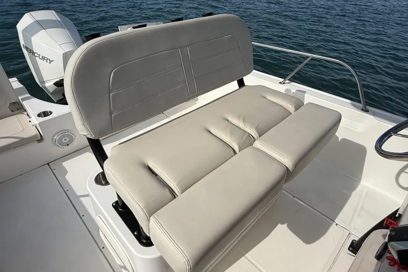 Slide: The Image of 2024 Boston Whaler 210 Montauk boat interior with cushioned seating and Mercury engine. - 21