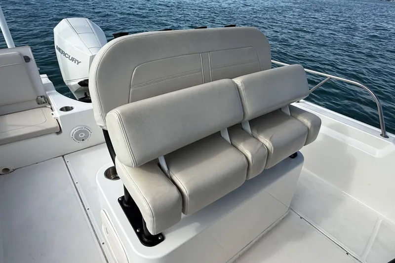 Slide: The Image of 2024 Boston Whaler 210 Montauk boat interior with cushioned seating and Mercury engine. - 22