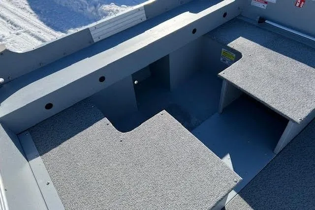 Slide: The Image of 2026 Lund SSV-16 boat interior with gray carpeted seating and storage compartments. - 12