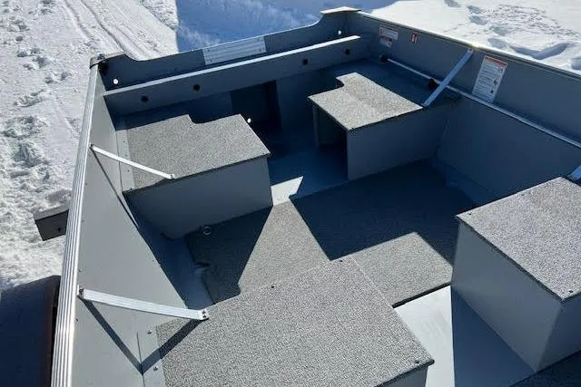 Slide: The Image of 2026 Lund SSV-16 boat interior with gray seating and storage compartments on snowy ground. - 16