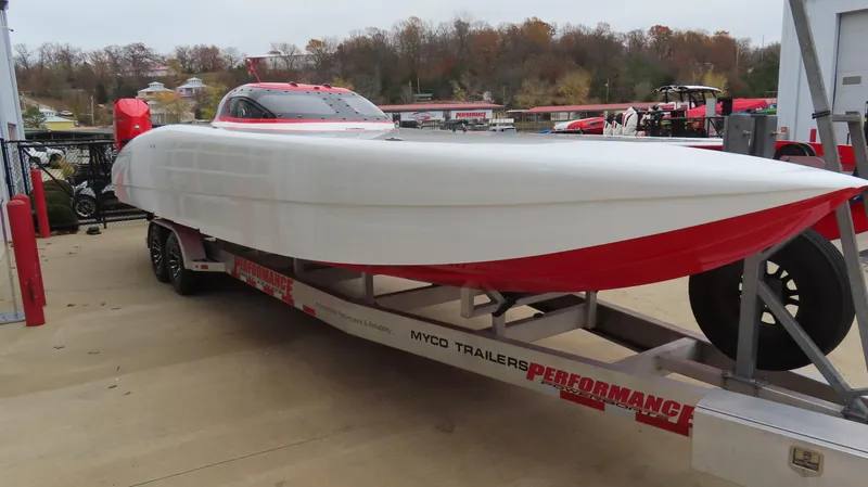 Slide: The Image of 2019 Doug Wright 32 powerboat on trailer, red and white design, parked outdoors. - 4