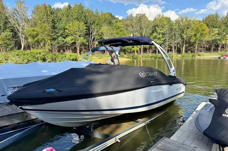 Slide: The Image of 2017 Cobalt 220S boat covered at dock, surrounded by trees and calm water. - 2