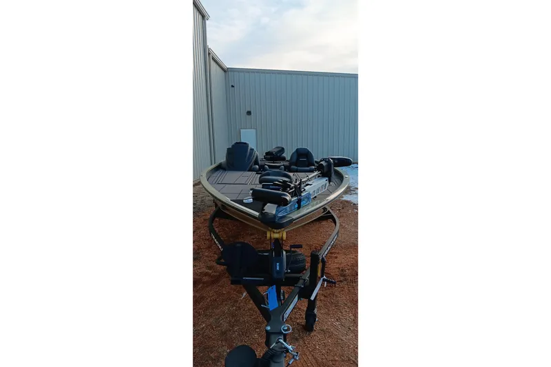Slide: The Image of 2026 Tracker Savage 215 boat on trailer, parked beside a metal building. - 2