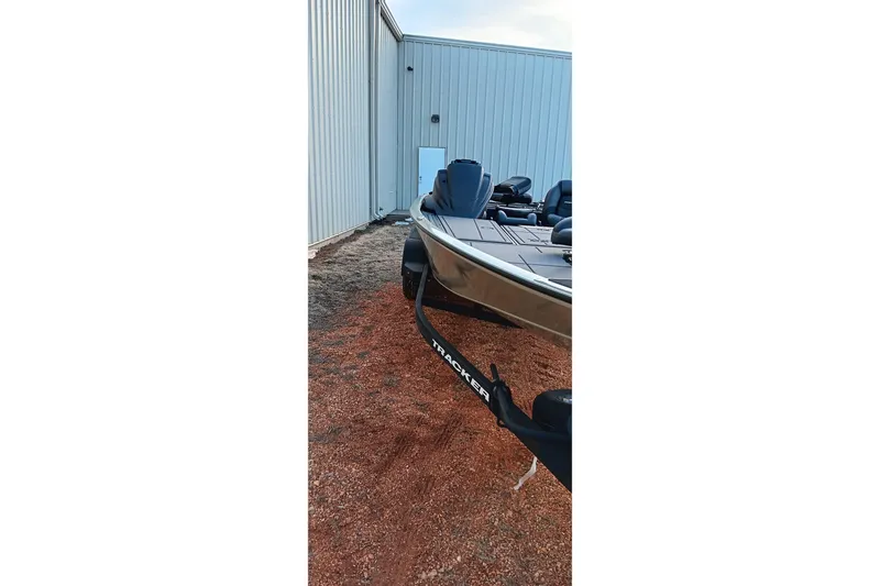 Slide: The Image of 2026 Tracker Savage 215 boat parked beside a metal building. - 3