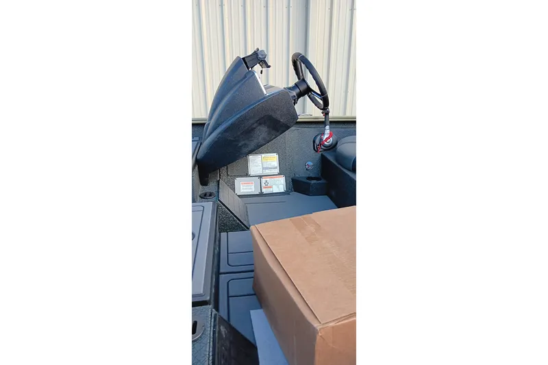 Slide: The Image of 2026 Tracker Savage 215 boat interior with steering wheel and cardboard box. - 7