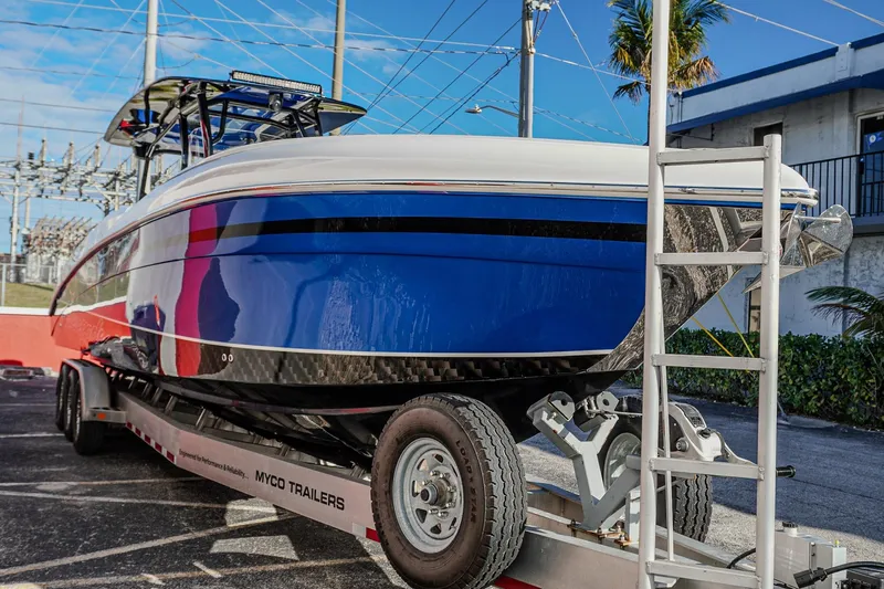 Slide: The Image of 2024 Renegade 38 Open boat on trailer, vibrant blue hull, parked outdoors. - 7